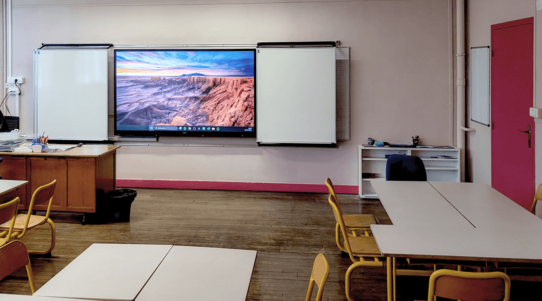 Pack interactif Easypitch Flash dans une salle de classe primaire, le pack se compose d’un écran interactif pour l’éducation et de tableaux blancs coulissants en mode ouverts